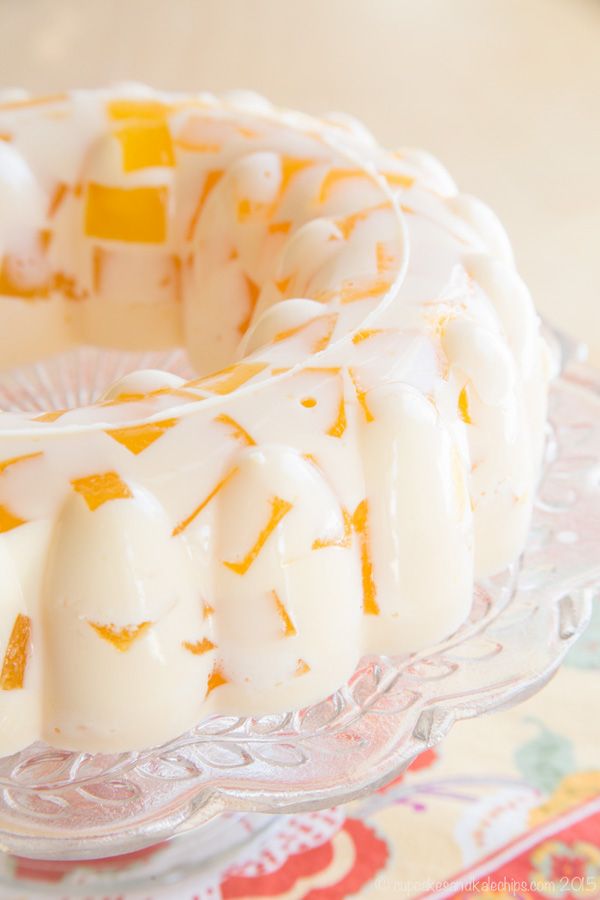 a cake sitting on top of a glass plate covered in icing and orange slices