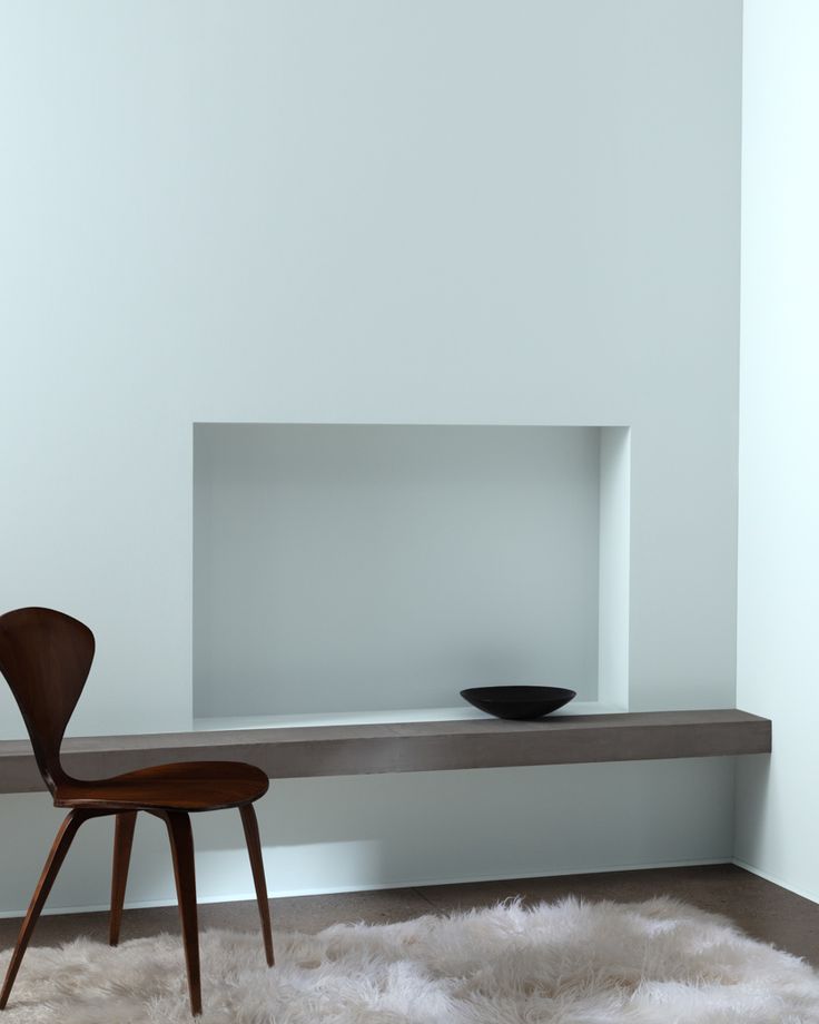 a chair sitting on top of a white rug next to a shelf filled with a bowl