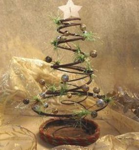 a small christmas tree made out of wire and wood with green leaves on top, sitting in a bowl