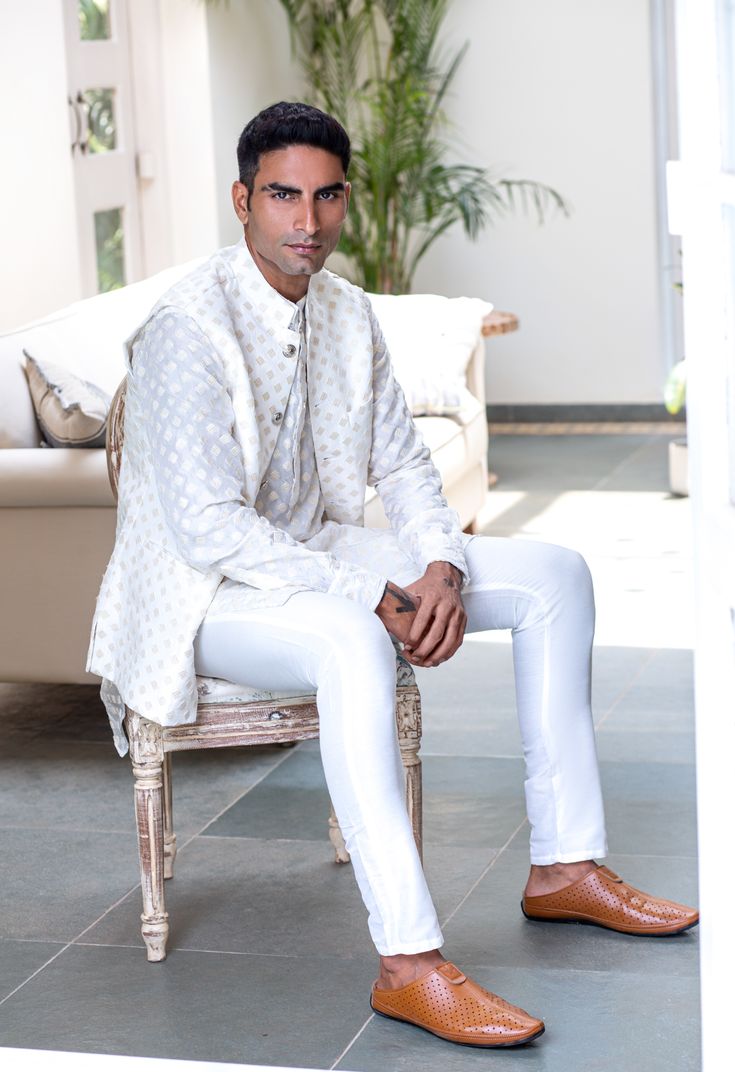 Embroidered bundi jacket in a white and gold art silk base fabric. This jacket is paired with a matching kurta and white pants.
 

Size Chart For Men





	
	
					Men's Size Chart
		

		
		
						
				Size Chart For Men
				Custom Size Measurement Guide
			
			
				
				
				Custom Size Measurement Guide
1. Take your measurements at ease…don’t hold your breath!
2. Be a little generous with the measurements. It’s always easier to take the garment in than to take it out.
3. We do rely on our clie White Bandhgala With Gota Work For Festive Occasions, Festive White Bandhgala With Gota Work, Designer Wear Fitted White Nehru Jacket, Designer White Fitted Nehru Jacket, Designer Fitted White Nehru Jacket, White Fitted Nehru Jacket For Designer Wear, White Chikankari Embroidery Outerwear For Eid, White Bandhgala With Gota Work For Eid, White Bandhgala With Gota Work For Diwali