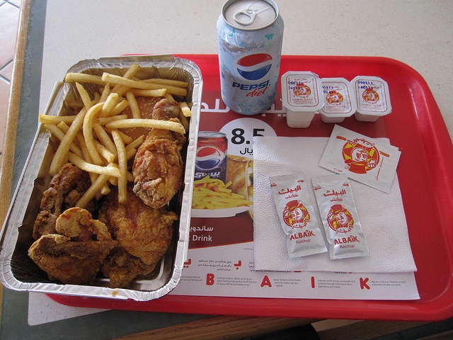 a tray with chicken, french fries and soda on it