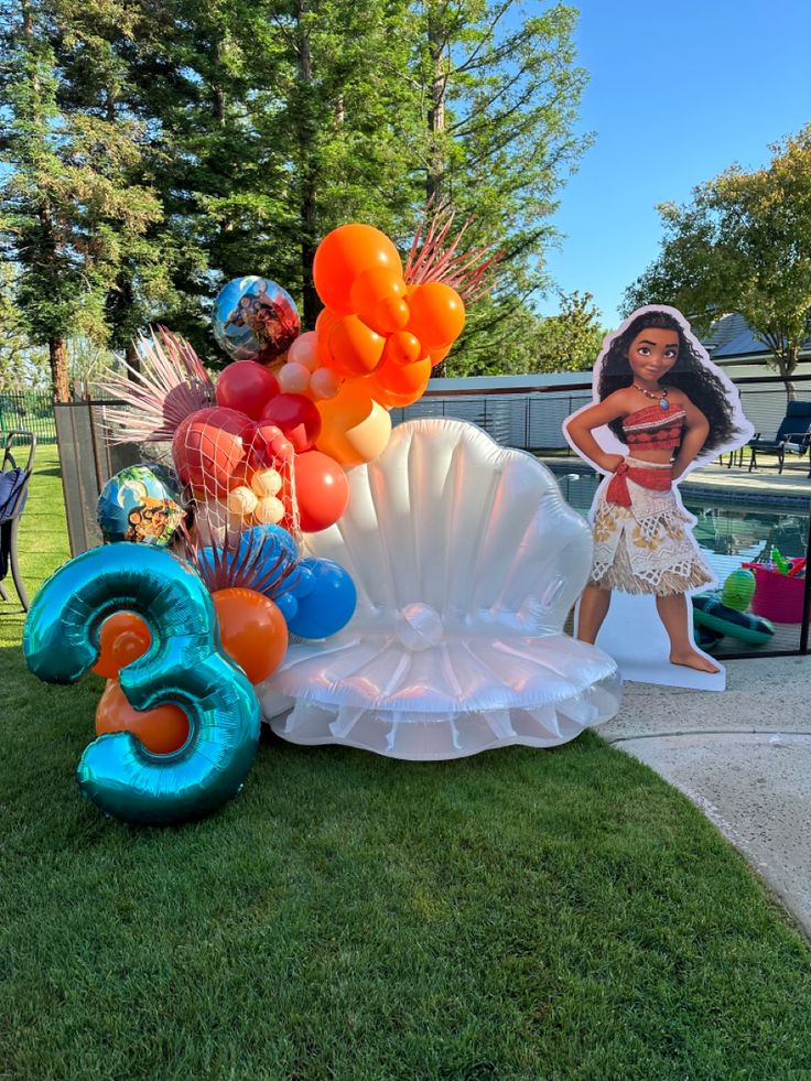 an inflatable shell with balloons and other decorations on the lawn next to it