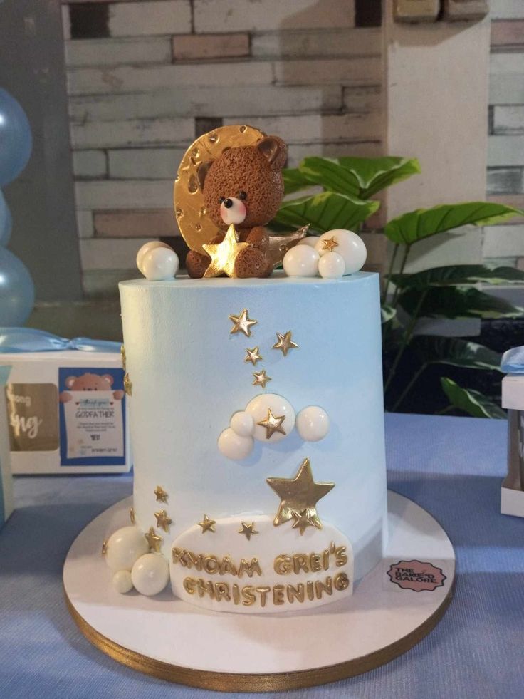 a teddy bear sitting on top of a white and blue cake with gold stars around it