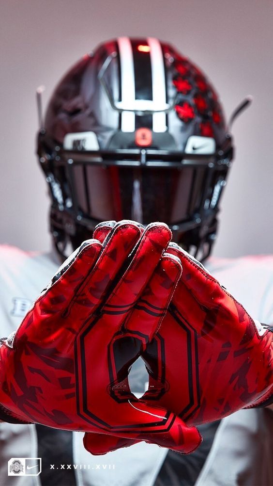 a football player wearing a helmet and holding his hand up to the camera with both hands