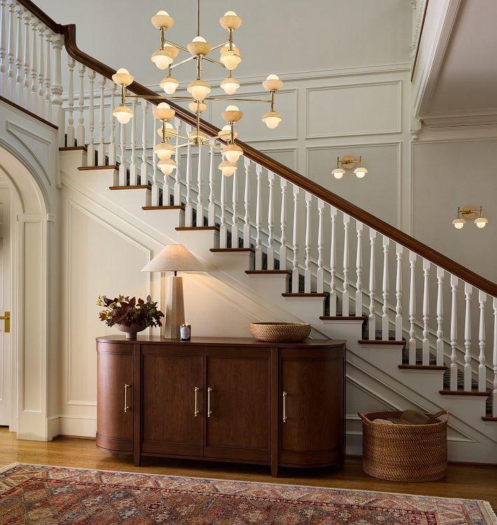 a living room area with a rug, cabinet and staircase leading up to the second floor