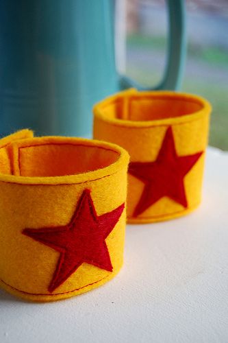 two yellow cups with red stars on them sitting next to a teapot and cup holder