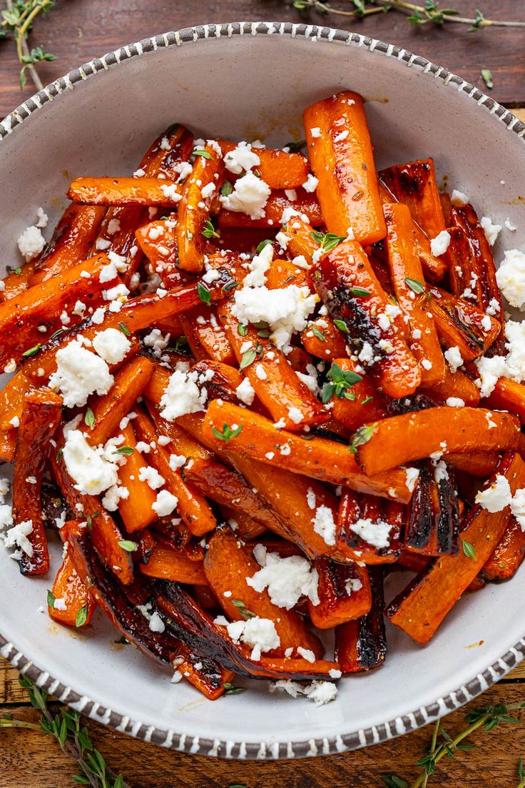 a bowl filled with carrots and feta cheese on top of a wooden table