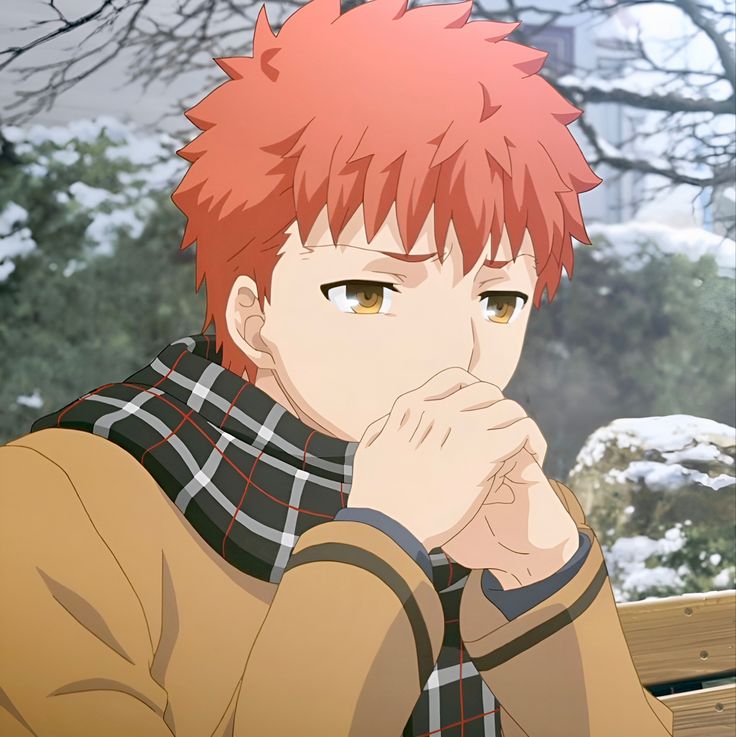 a man with red hair sitting on top of a bench in front of snow covered trees