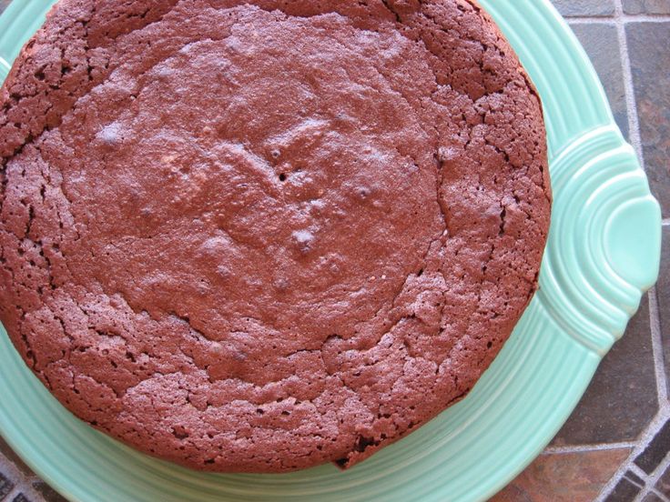 a chocolate cake sitting on top of a green plate next to a pink and white border