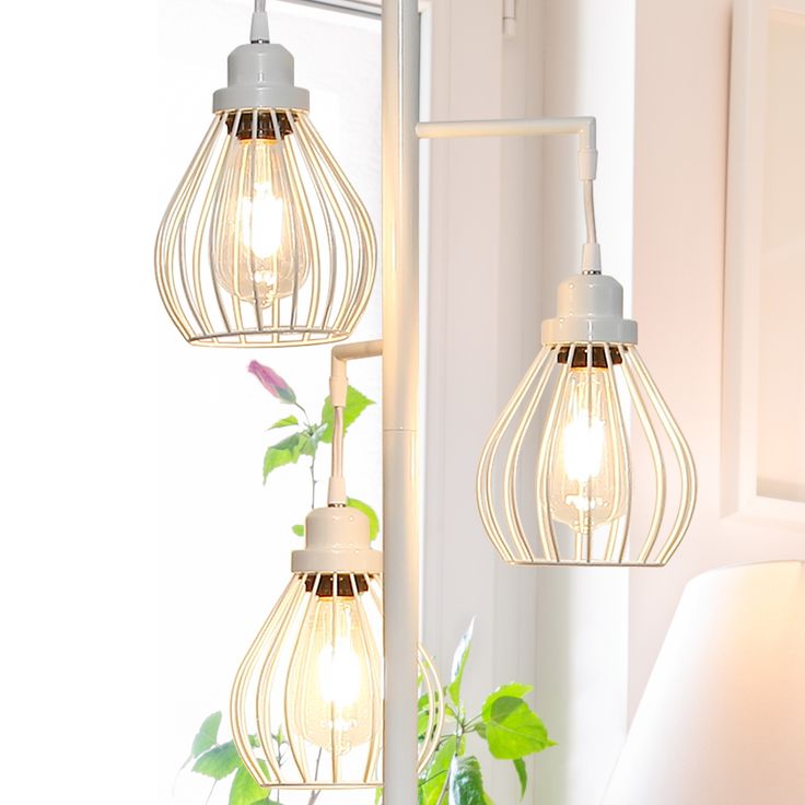 two light fixtures hanging from a wall next to a mirror and potted plant in front of a window