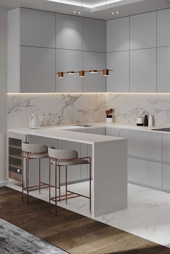 a modern kitchen with marble counter tops and white cabinets, along with bar stools