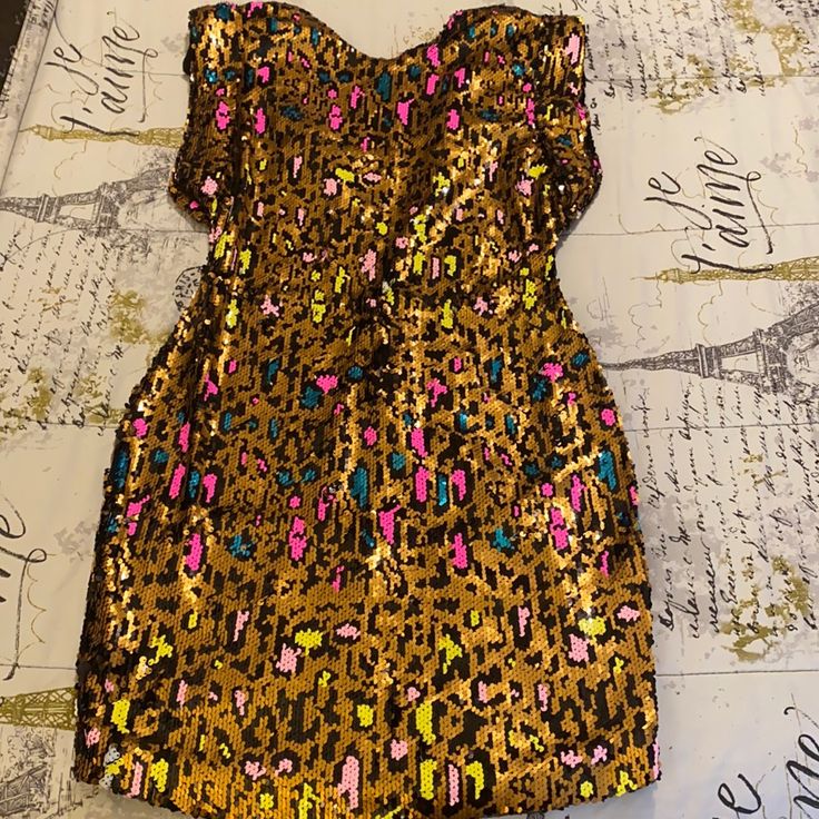 a gold and pink sequinned dress laying on top of a tablecloth covered with writing