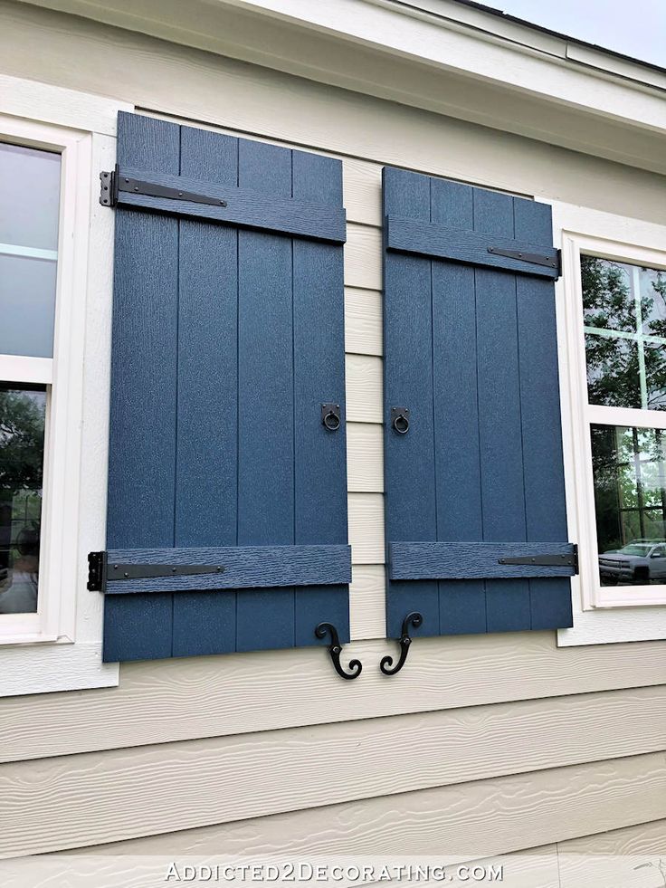 two blue shutters on the side of a house with white trim and black handles