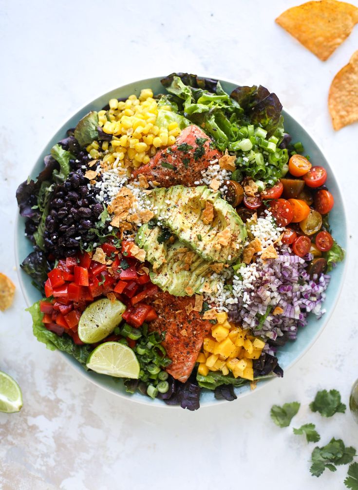 a colorful salad with avocado, tomatoes, black beans, corn and limes