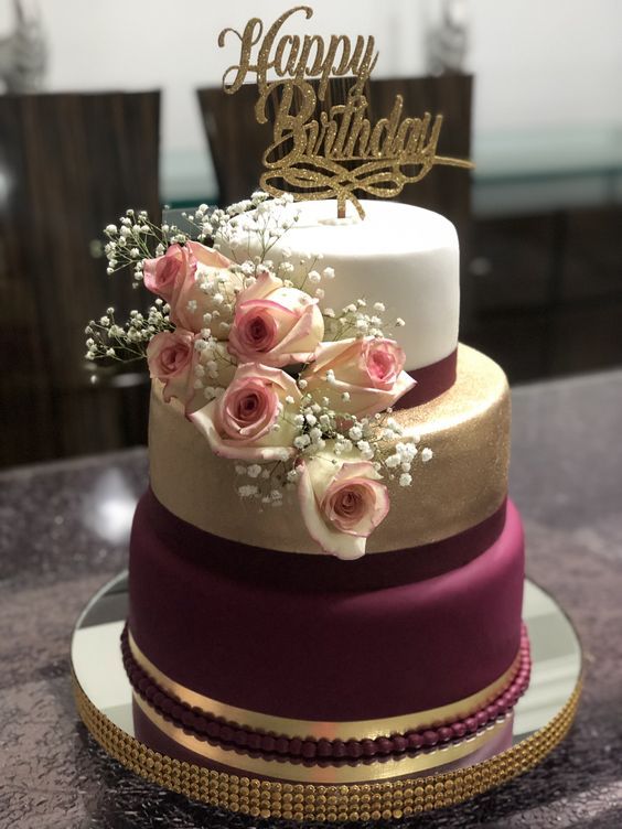 a three tiered cake decorated with flowers and the words happy birthday written on top