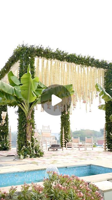 an outdoor wedding setup with flowers and greenery on the side, near a swimming pool