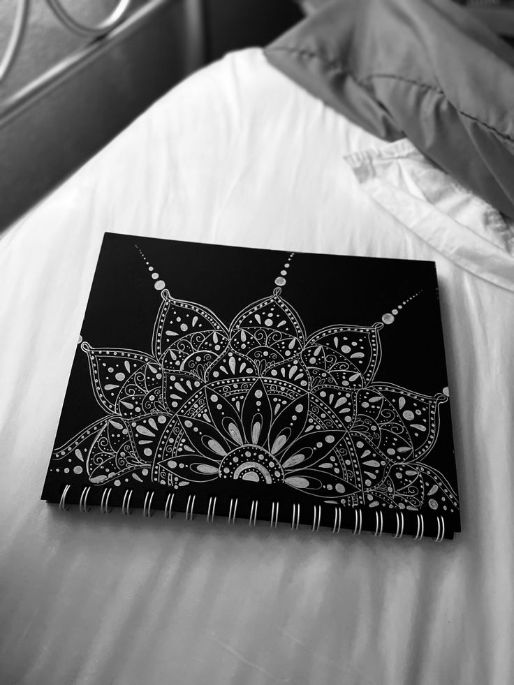 a black and white photo of a bed with an intricate design on the front cover