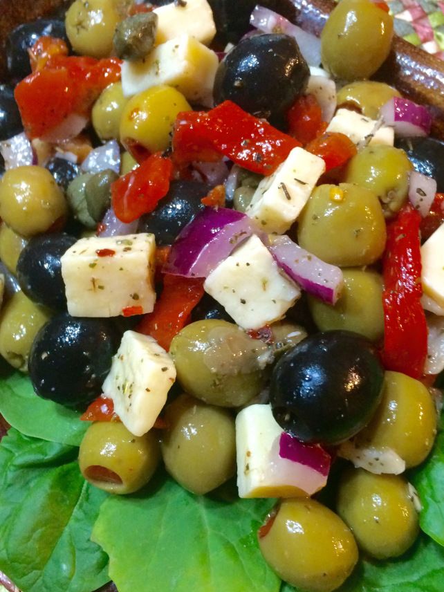 a salad with olives, tomatoes, cheese and lettuce on a plate