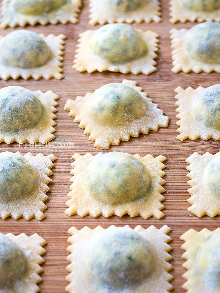 small ravioli shells covered in powdered sugar on a wooden surface