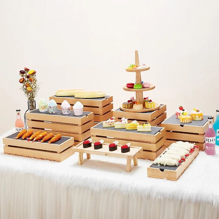 an assortment of desserts and pastries displayed on a white tablecloth covered table