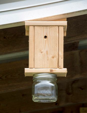 a mason jar hanging from the side of a wooden structure with a birdhouse attached to it