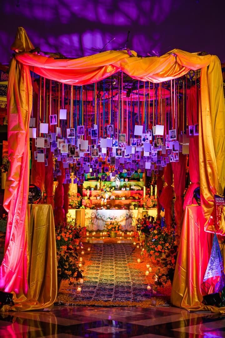 a decorated stage with orange and pink draping on the sides, surrounded by candles