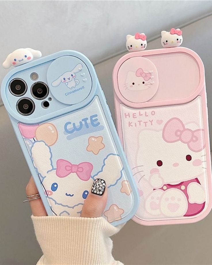 a person holding two cell phones with hello kitty cases on them, one is pink and the other is blue