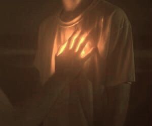 a man holding his hands up in the dark with light shining on him from behind