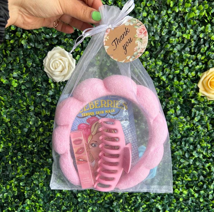 a pink comb and hair brush in a plastic bag with flowers on the side next to it