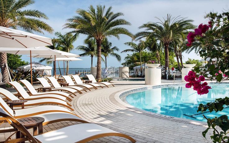 lounge chairs and umbrellas near an outdoor swimming pool