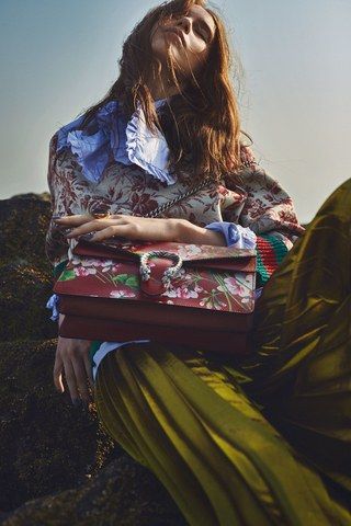 a woman sitting on top of a pile of luggage with her hands in her pockets