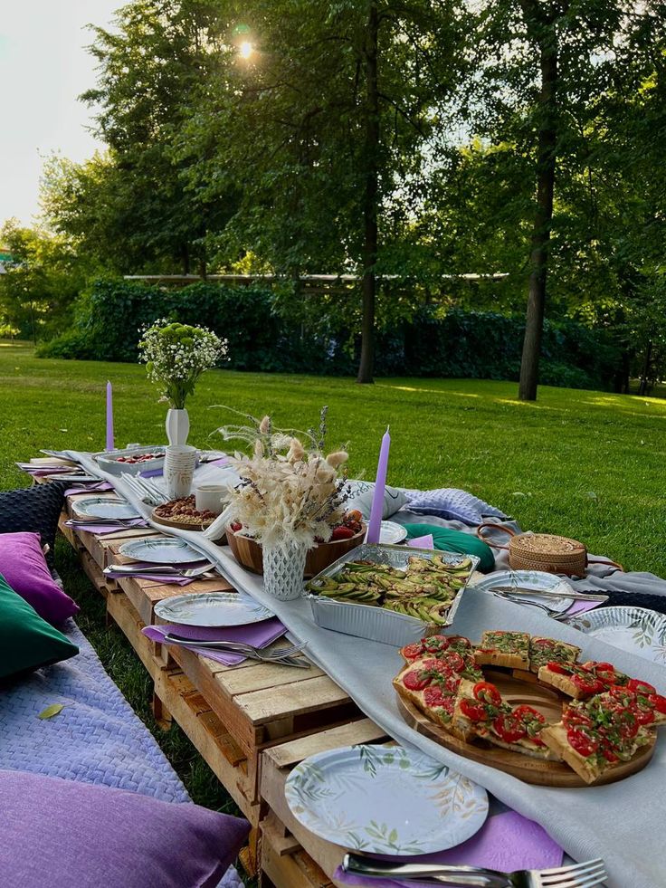 a long table with plates and food on it in the middle of a grassy area