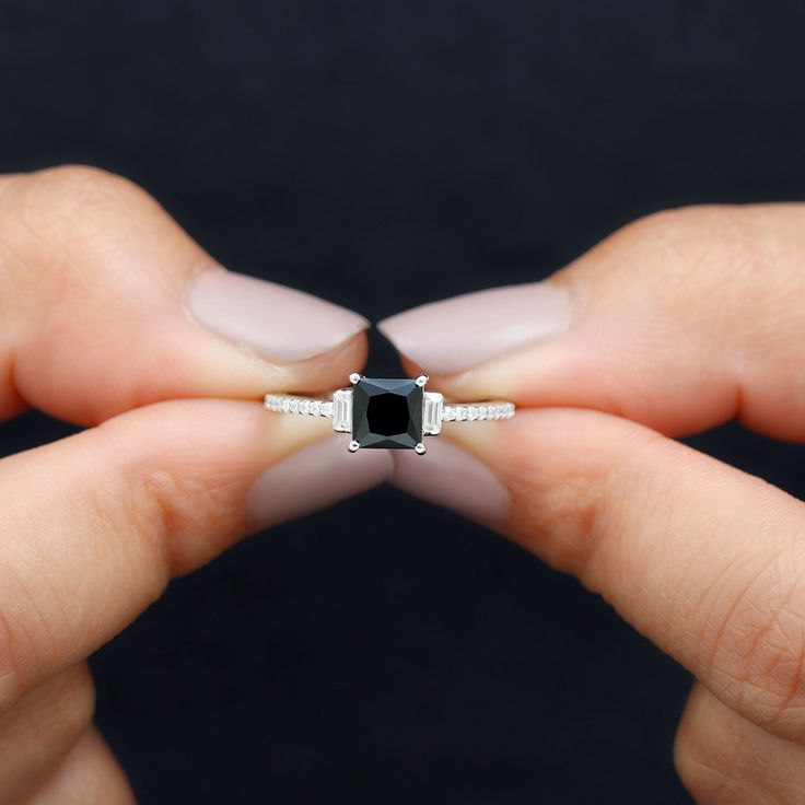 two hands holding an engagement ring with a black diamond