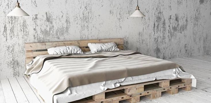 a bed made out of wooden pallets in a room with concrete walls and flooring