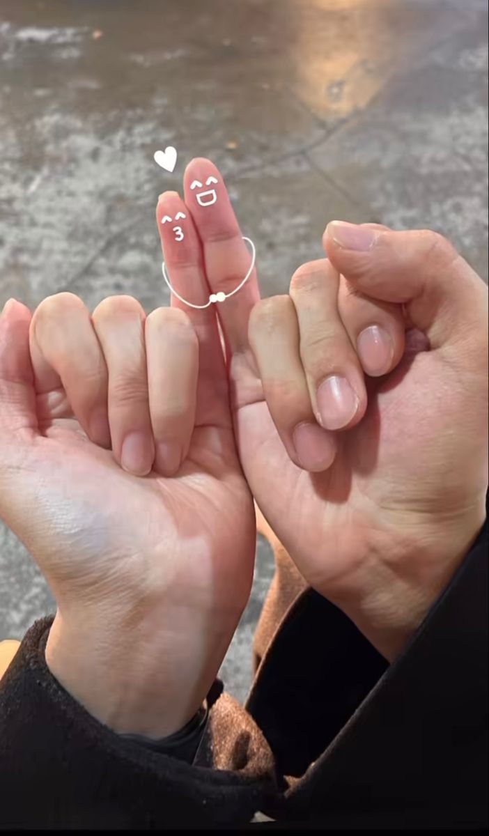 someone holding their fingers up with two hearts drawn on them