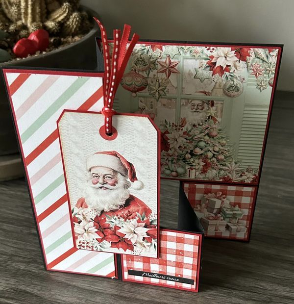 two christmas gift tags with santa clause on them sitting next to a potted plant