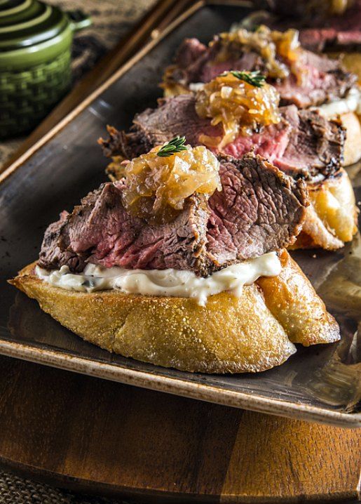 a roast beef sandwich is on a wooden platter