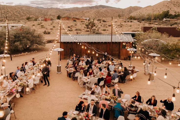 a group of people sitting around tables in the desert