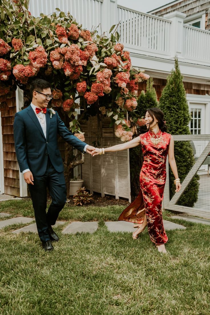 a woman in a red dress and a man in a black suit are holding hands