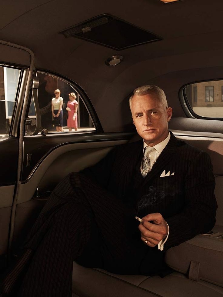 a man sitting in the back seat of a car wearing a black suit and tie