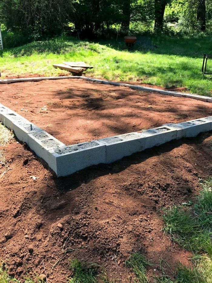 a concrete block laying on top of dirt in a yard with trees and grass behind it