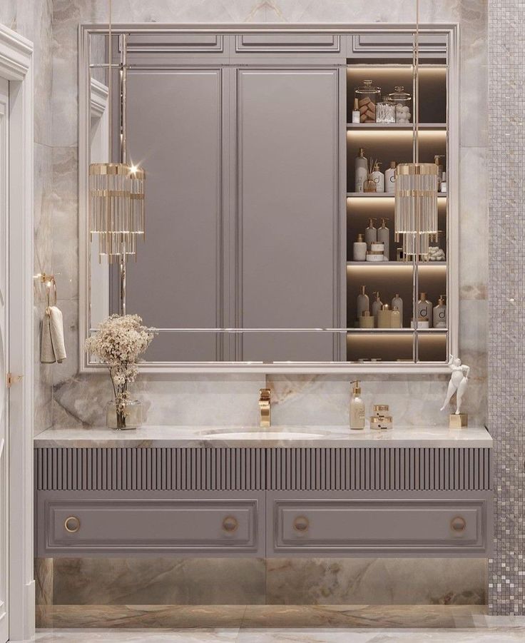 an elegant bathroom with marble counter tops and gray cabinetry, along with gold accents