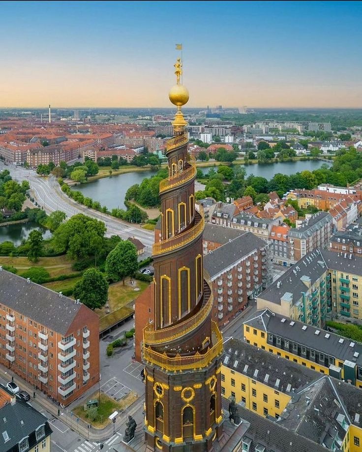 an aerial view of a city with tall buildings and a river in the background at sunset