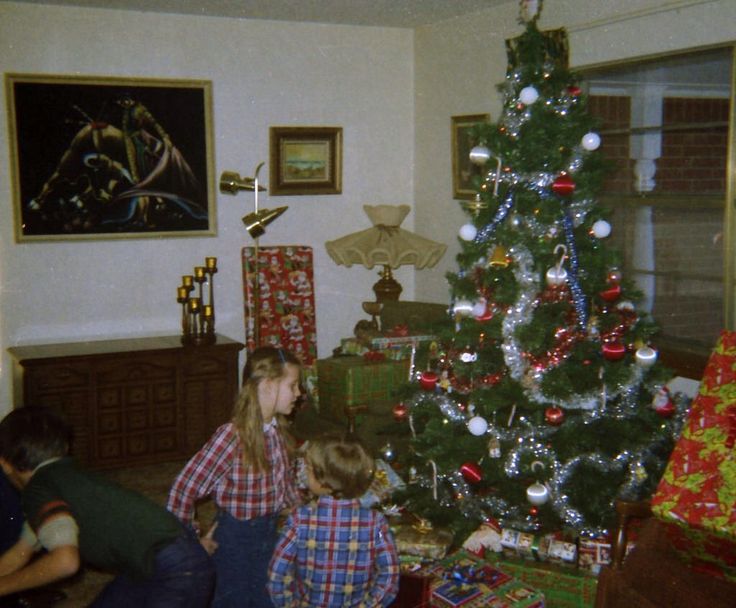 two children sitting in front of a christmas tree