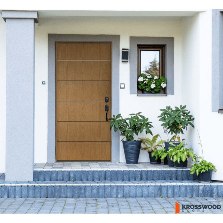 two potted plants sit in front of a house with a wooden door and window