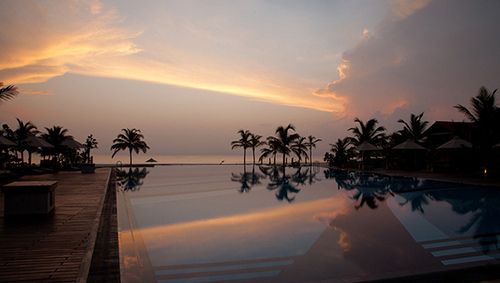 an empty swimming pool at sunset with palm trees in the background and water reflecting on the ground