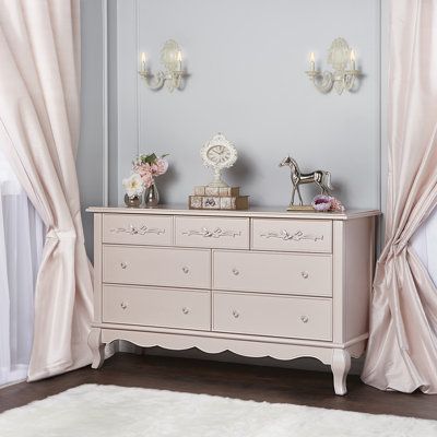 a white dresser sitting next to a window covered in pink curtained drapes and curtains