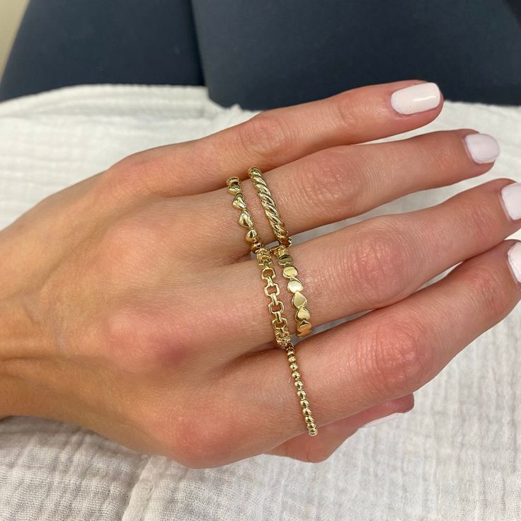 a woman's hand with three gold rings on her fingers and one ring in the middle