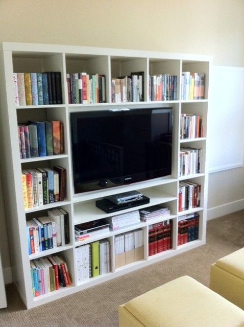 a living room filled with furniture and a flat screen tv on top of a book shelf