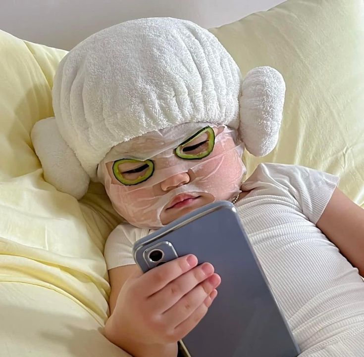 a baby wearing a mask and holding a tablet in its hands while laying on a bed